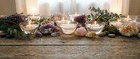 Healing crystals and gemstones arranged with burning candles on rustic wooden surface creating peaceful meditation and wellness atmosphere.