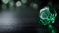Sparkling emerald crystal on dark textured surface with green bokeh background creates luxurious gemstone composition with dramatic lighting and reflections.