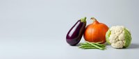 Fresh organic vegetables including eggplant, pumpkin, cauliflower and green beans arranged on white background for healthy cooking and nutrition concepts.