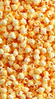 Freshly popped buttery popcorn filling the frame, golden yellow kernels with white fluffy centers creating a textured snack background.