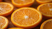 Fresh juicy orange cut in half showing detailed pulp texture and natural citrus segments with water droplets in warm lighting on dark background.