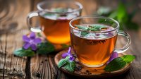 Aromatic herbal tea in transparent glass cups with fresh mint leaves and purple flowers on rustic wooden background, perfect for wellness, relaxation and healthy lifestyle concepts.