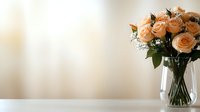 Fresh peach roses arranged in clear glass vase with greenery against neutral beige background, elegant floral composition for wedding, home decor, and celebrations.