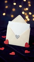 Open cream envelope with white card and silver heart charm on dark velvet background with red hearts and golden bokeh lights. Perfect for wedding invitations, love letters, Valentine's Day greetings, and romantic correspondence designs.