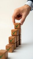 Businessman hand placing wooden cube with green checkmark building success steps concept for goal achievement and business growth strategy.