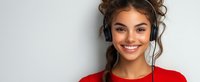 Young woman with bright smile wearing red sweater and headphones against light background, positive lifestyle portrait for advertising and social media content.