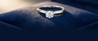 Elegant diamond solitaire engagement ring with brilliant cut stone on dark blue velvet jewelry box, luxury wedding proposal symbol for romantic occasions.