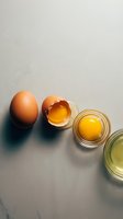 Fresh brown eggs with golden yolks separated in glass bowls on neutral background for cooking and baking recipes.