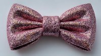 Pink glittery bow tie with sparkly texture isolated on white background for fashion accessories, formal wear, party decorations and craft projects.