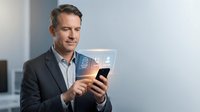 Professional middle-aged Caucasian businessman in suit using smartphone with digital holographic interface in modern office environment for technology concepts.