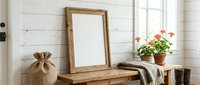 Rustic wooden frame mockup leaning on a farmhouse bench with white shiplap wall, burlap sack, cozy blanket, and blooming geraniums near window.