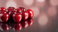 Fresh red cranberries with water droplets on reflective surface with soft bokeh background for healthy eating and holiday cooking concepts.