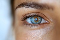 Close up macro shot of bright blue eye with long eyelashes and detailed iris pattern showing natural beauty and vision health concept.