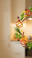 Flying spices and herbs with bell pepper slices, basil leaves, cinnamon sticks and star anise falling in modern kitchen for culinary cooking concepts.