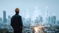 Construction engineer in hard hat overlooking city skyline with digital building projections, representing urban development and smart city technology.