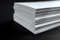 Stack of white paper sheets on black leather surface, showing layered edges against dark background for business, printing, and office documentation.