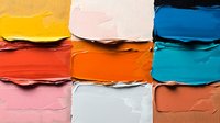 Vibrant oil paint swatches in yellow, orange, pink, blue and coral tones arranged in grid pattern showing thick textured strokes and layered palette knife application.