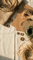 Natural eco-friendly craft supplies with jute fabric, raffia, wooden buttons and hemp twine arranged on neutral linen background for sustainable DIY projects.