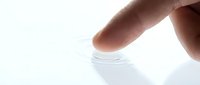 Finger touching water surface creating ripple effect on white background, isolated for design use.