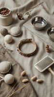 Rustic flat lay with natural wool felt balls, wooden bowls, dried flowers and craft supplies on beige linen fabric for handmade artisan projects.