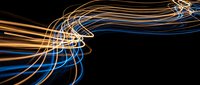 Dynamic light trails creating flowing curves in blue and orange colors against black background for modern digital design projects.