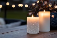 Glowing decorative candles on wooden table with bokeh lights in background create cozy evening atmosphere. Romantic outdoor setting for special occasions.