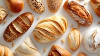 Assortment of freshly baked artisan bread loaves with various crusts, shapes and toppings on white background, showcasing bakery products.