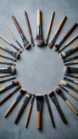 Professional makeup brushes arranged in circular pattern on concrete surface for beauty and cosmetics applications.