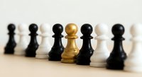 Golden pawn standing out among black and white chess pieces on wooden surface, representing leadership, uniqueness and strategic thinking in business.
