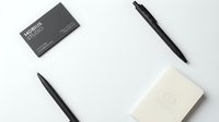 Minimalist business stationery mockup with black pens, business card and notepad on white background for branding and corporate identity design.