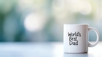 White ceramic mug with World's Best Dad text on blurred turquoise background with bokeh lights. Father's day celebration concept with copy space.