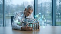 Senior male professional examining architectural model with digital technology overlay, representing smart building design and innovation for construction industry applications.