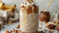 Creamy chia seed pudding topped with whipped cream, granola, and crushed nuts in a glass jar, ready for breakfast or dessert preparation.