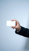 Professional businessman hand holding blank white business card against clean background for corporate branding and marketing materials.