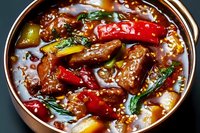 Spicy Asian beef stew with tender meat chunks, colorful bell peppers, and fresh herbs in savory sauce garnished with sesame seeds. Served in copper bowl.