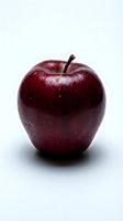 Dark red apple with stem isolated on white background, suitable for food packaging, nutrition labels, and healthy eating designs.