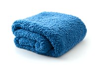Folded soft blue microfiber towel on white background, isolated cleaning cloth with fluffy texture and cozy appearance for household and spa use.