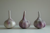 Three whole garlic bulbs arranged in row showing purple streaked white papery skin against neutral background, minimalist food photography composition.