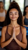 Young mixed-race woman practicing yoga meditation with prayer hands pose in fitness studio. Mindfulness wellness exercise class instructor concept.