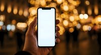 Hand holding smartphone with blank white screen against blurred golden bokeh lights background at night for mobile app mockup and digital display presentation.