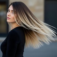 Young woman with long blonde ombre hair in motion wearing black sweater outdoors in natural daylight for beauty and lifestyle concepts.