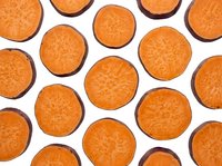 Fresh carrot slices arranged in repeating pattern on white background. Healthy vegetable ingredient for cooking, nutrition and diet concepts.