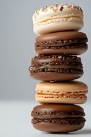 Stack of chocolate and vanilla French macarons with sprinkles and filling against light background, close up view of delicate almond meringue cookies.