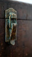 Vintage brass door latch with patina on weathered wooden surface showcasing antique hardware craftsmanship and rustic architectural detail.