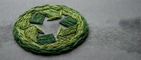 Green embroidery floss thread skein for needlework crafts and cross stitch projects on neutral fabric background.