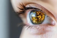 Close-up of blue eye with digital circuit reflection in pupil showing golden technology pattern, representing artificial intelligence and future vision concept.