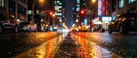Wet asphalt street at night with colorful city lights reflecting on rain-soaked pavement creating atmospheric urban scene with blurred traffic and glowing streetlights.