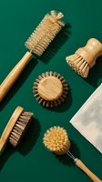 Eco-friendly bamboo cleaning brushes with natural sisal bristles and linen cloth on green background, sustainable zero waste kitchen tools flat lay.