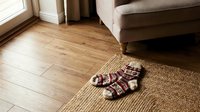 Pair of striped socks placed on natural jute rug in modern living room with wooden flooring and upholstered sofa.