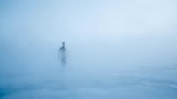 Solitary figure standing in dense fog on snowy landscape, creating atmospheric and eerie mood suitable for conceptual, editorial, and psychological themes.
